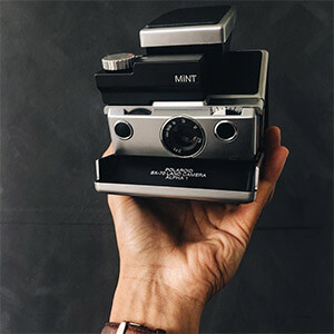 Hand taking Vintage Polaroid SX-70 Camera SLR670-S